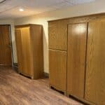 Three wooden wardrobes in a room with laminate flooring.