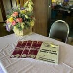 Brochures and flower arrangement on event table.
