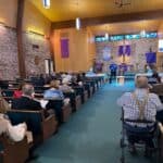 Congregation attending service in a church with purple banners.