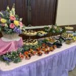 Catering buffet table with flowers and assorted dishes.