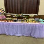 Catered buffet table with various dishes and floral arrangement.