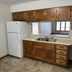 Wooden kitchen cabinets with white refrigerator and sink.