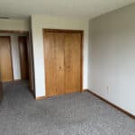 Empty room with closed wooden doors and gray carpet.