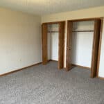 Empty room with carpet and open closets.