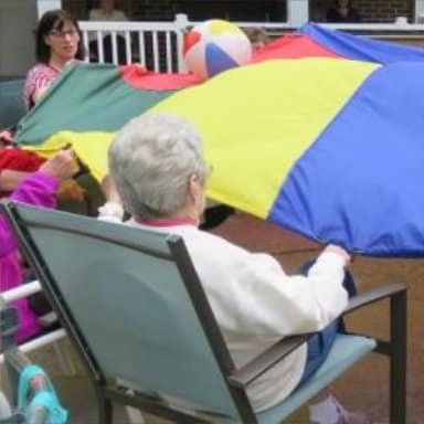 Senior citizens playing with a colorful parachute.
