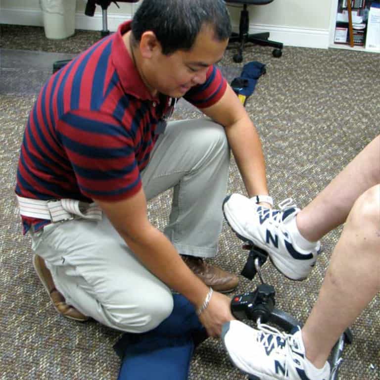 Man fitting orthopedic brace on patient's leg.